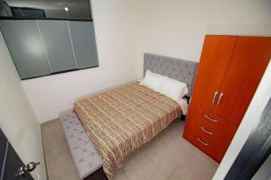 a small bedroom with a bed and a mirror at Moderno y acogedor departamento in Tacna