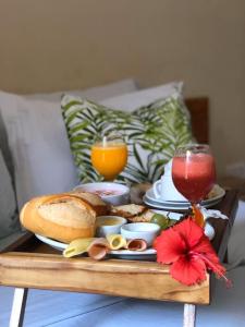 a tray of food with bread and drinks on a table at Pousada Trancoso Guarapari in Guarapari
