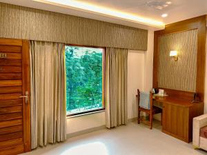 a bedroom with a desk and a large window at Hotel Ananda Kashi in Varanasi