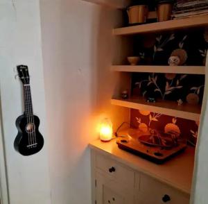 a room with a guitar on a shelf with a candle at Jackdaw Cottage-Beautiful Cottage, Town Centre in Wimborne Minster