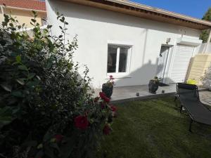 uma casa branca com um quintal com um banco e rosas em Studio proche Paris et aéroport d'Orly em Orly