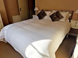 a large white bed with two pillows on it at Jackdaw Cottage-Beautiful Cottage, Town Centre in Wimborne Minster