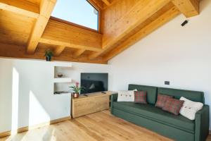 a living room with a green couch and wooden ceilings at Chalet M in Val di Zoldo