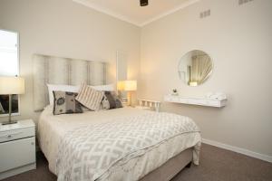 a white bedroom with a bed and a mirror at Shepherd's Rest in Mossel Bay