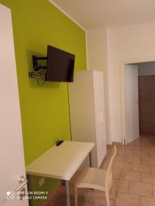 een kamer met een tafel en een tv aan een groene muur bij Casa peo in Benevento