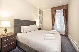 Un dormitorio con una gran cama blanca y una ventana en Historic Whitehall flat in SW1 by UnderTheDoormat en Londres
