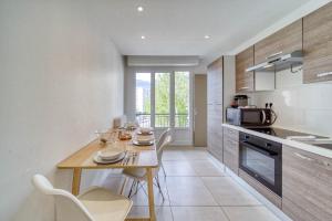 een keuken met een houten tafel en stoelen in een kamer bij Le stade Clémenceau in Grenoble