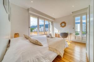 a bedroom with a large bed with white sheets and windows at Le stade Clémenceau in Grenoble