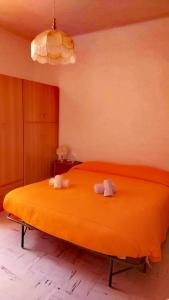 1 dormitorio con 1 cama grande de color naranja y 2 toallas en Casa vacanze nel Parco Nazionale della Majella, en Montenerodomo