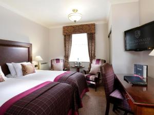 Habitación de hotel con cama, escritorio y TV. en Macdonald Kilhey Court Hotel & Spa en Wigan