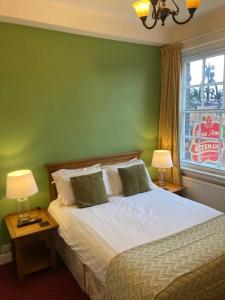 1 dormitorio con 1 cama con pared verde en The King's Arms en Boston