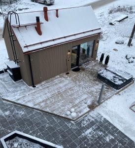 een klein gebouw met een met sneeuw bedekt dak bij Guesthouse with sauna & hot tub in Nokia