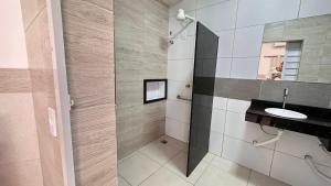 a bathroom with a shower with a sink and a mirror at Pousada São Luiz in Aracaju