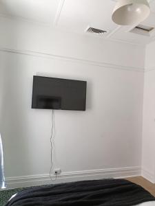 TV colgada en la pared de un dormitorio en Beautiful Queen Room 1Min Walk to Station with 60Inch TV, en Sídney