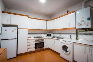 een keuken met witte kasten en een wasmachine en droger bij QH Gran Via 01 in Granada