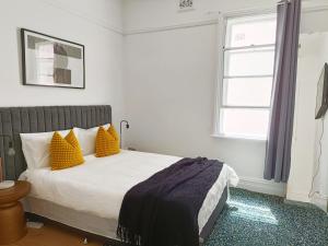 Un dormitorio con una cama con almohadas amarillas y una ventana. en Beautiful Queen Room 1Min Walk to Station with 60Inch TV, en Sídney