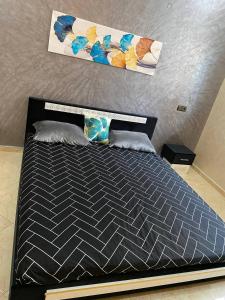 a bedroom with a bed with a black comforter at Appartement calme in Fez