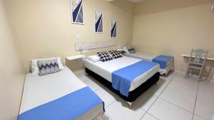 a bedroom with two beds and a table and a chair at Pousada São Luiz in Aracaju