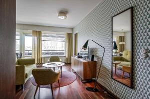 a living room with a mirror and a table and chairs at Forenom Serviced Apartments Espoo Tapiola in Espoo