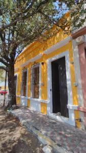 a yellow building with a door and a tree at Casa del Desierto in Guadalajara