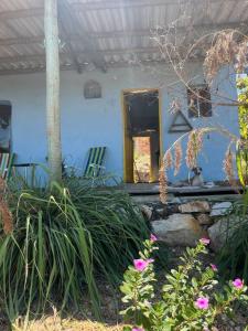 una casa con porche con sillas y flores en CasaTupy Pousada, en Botumirim