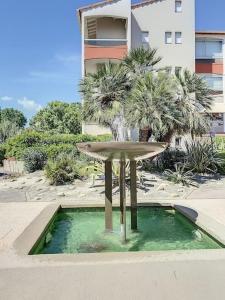 a fountain with a palm tree in front of a building at La Brise Marine ~ 300m mer~Piscine~Clim~Wifi~Calme in Argelès-sur-Mer