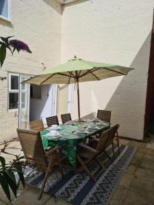 a table with a green umbrella and chairs at 6 En-Suite Bedrooms; Garden; Driveway;Pet Friendly in Bournemouth