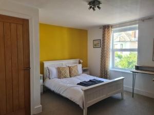 a bedroom with a bed with a yellow wall at 6 En-Suite Bedrooms; Garden; Driveway;Pet Friendly in Bournemouth