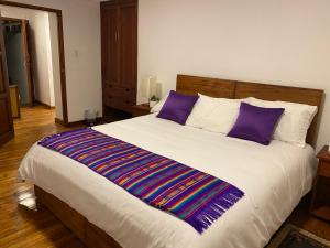 ein Schlafzimmer mit einem großen Bett mit lila Kissen in der Unterkunft Hotel Colonial - Casa Francisco in Quito