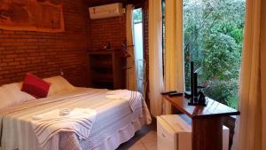 um quarto com uma cama, uma secretária e uma janela em Pousada Alfa e Ômega em Alto Paraíso de Goiás