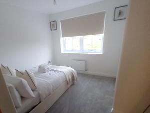 a white bedroom with a bed and a window at Luxury 3 bedroom house on the outskirts of Newcastle near to Hadrians Wall in Newcastle upon Tyne