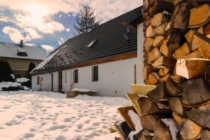 a house in the snow with a pile of logs at Osada Pogodno 2 in Miłków