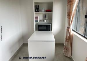 a kitchen with a microwave on a white counter at APARTAMENTO ENCANTADO V. MARIA 9 in Foz do Iguaçu