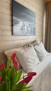 eine Wand mit einem Gemälde über einem Bett mit roten Tulpen in der Unterkunft Green Valley vacation homes in Žocenes Ciems