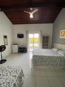a bedroom with two beds and a ceiling fan at Suítes Itapoã in Ubatuba