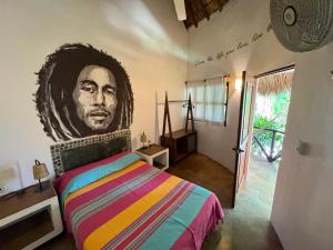 a bedroom with a painting of a man on the wall at One Love Hostal Puerto Escondido in Puerto Escondido