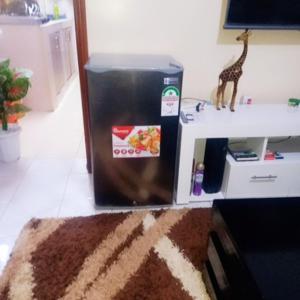 einen Kühlschrank in einem Zimmer mit einem Tisch und einer Giraffe mit Spielzeug in der Unterkunft @princess Dee in Meru