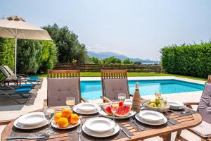 a wooden table with fruit on it next to a swimming pool at Armonia Villas in Lixouri