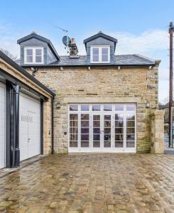 uma casa de tijolos com portas de garagem brancas em Luxury Mews House in Harrogate em Harrogate