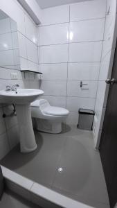 La salle de bains blanche est pourvue d'un lavabo et de toilettes. dans l'établissement CASONA PIURA, à Huancayo