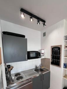 a kitchen with a sink and a microwave at face mer in Saint-Hilaire-de-Riez