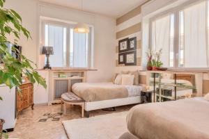 a bedroom with two beds and a desk and windows at Villa Aida in Milan