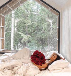 a woman laying on a bed with a bunch of roses at Leśna Kąpiel in Karpacz