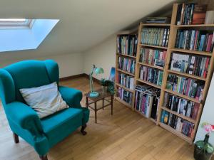 un salon avec une chaise bleue et des étagères remplies de livres dans l'établissement Ericeira Seaside Escape, à Ericeira