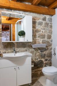 a bathroom with a white sink and a stone wall at House Wood in Orebić