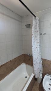 y baño con bañera, aseo y cortina de ducha. en Loren House en Luján de Cuyo