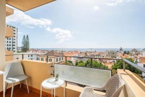 Un balcón con sillas y vista a una ciudad. en SUPER Platinum, en Funchal