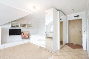 a white living room with a tv and a mirror at Apartament Grójec in Grójec