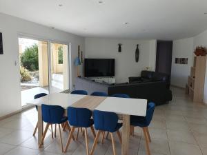 a living room with a white table and blue chairs at villa 15 personnes avec piscine et terrain de pétanque in Puysserampion