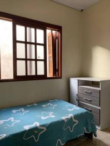 ein Schlafzimmer mit einem Bett, einer Kommode und einem Fenster in der Unterkunft Casa para 6 + piscina, in Rio Grande